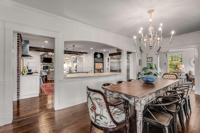 dining area with ornamental molding, dark wood-type flooring, and an inviting chandelier