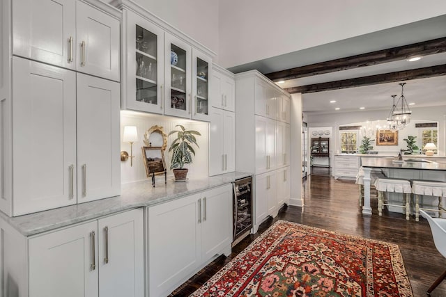 bar featuring beverage cooler, light stone counters, white cabinetry, dark hardwood / wood-style floors, and beam ceiling