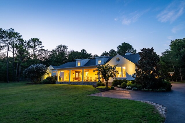 cape cod home featuring a lawn