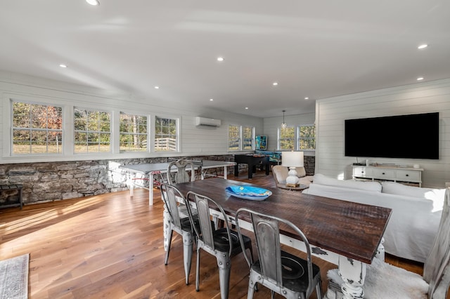 dining area with an AC wall unit and light hardwood / wood-style flooring