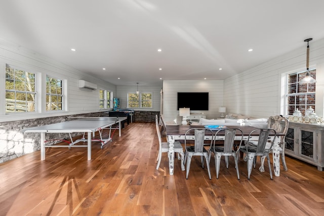 dining room with hardwood / wood-style floors and a wall unit AC