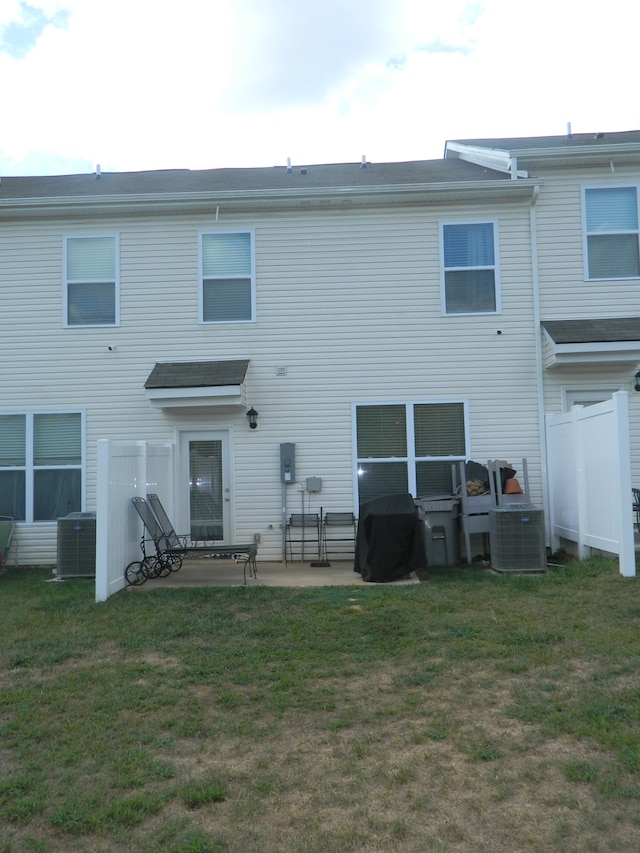 rear view of property with cooling unit, a patio, and a yard