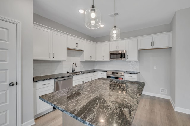 kitchen featuring appliances with stainless steel finishes, sink, a kitchen island, and white cabinets