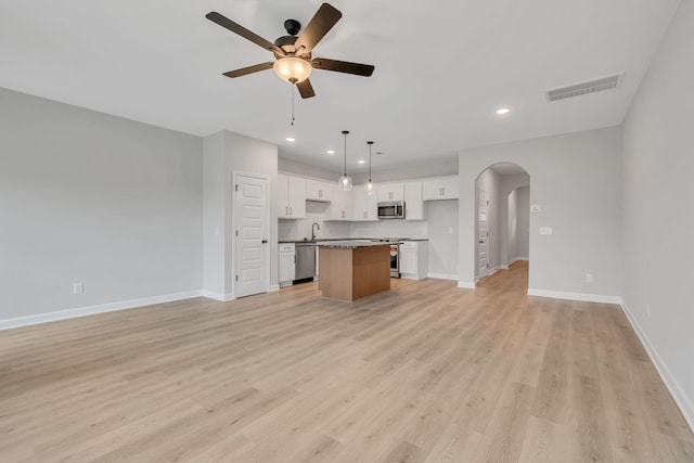 kitchen featuring light hardwood / wood-style flooring, hanging light fixtures, stainless steel appliances, white cabinets, and a kitchen island