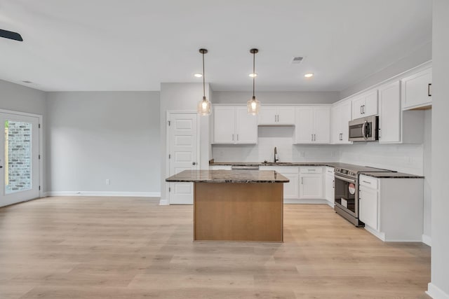 kitchen with appliances with stainless steel finishes, a center island, and white cabinets