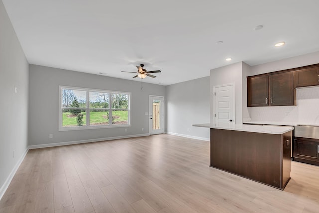 kitchen with ceiling fan, light hardwood / wood-style flooring, a kitchen island, and dark brown cabinets