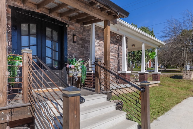 view of exterior entry featuring a porch and a yard