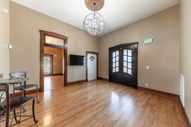 entrance foyer featuring light hardwood / wood-style flooring, french doors, and a chandelier