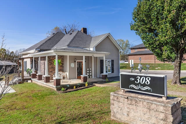 rear view of property with covered porch and a lawn