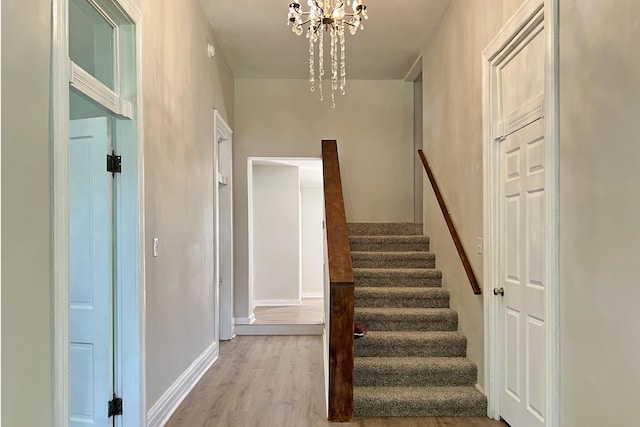 staircase with hardwood / wood-style flooring and a notable chandelier