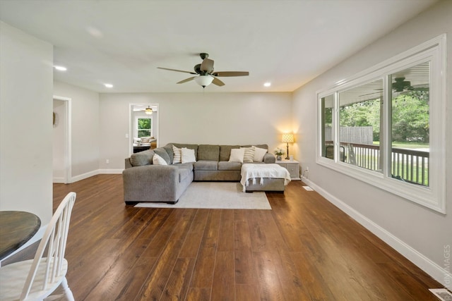 living room featuring dark wood-type flooring and ceiling fan