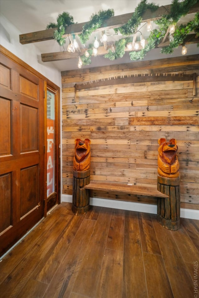 mudroom with dark wood-type flooring, beam ceiling, and wooden walls