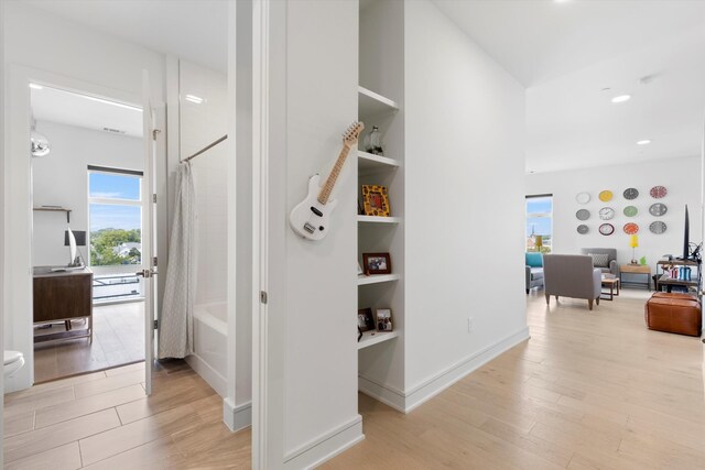 hallway featuring built in shelves and light wood-type flooring