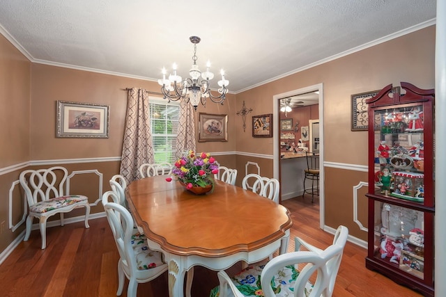 dining space featuring a textured ceiling, a chandelier, ornamental molding, and hardwood / wood-style flooring