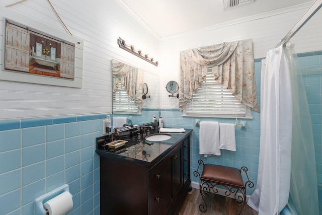 bathroom with tile walls, walk in shower, crown molding, and vanity