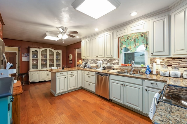 kitchen with white cabinets, kitchen peninsula, appliances with stainless steel finishes, and sink