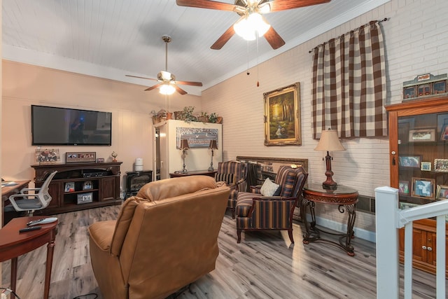 living room featuring ceiling fan, brick wall, and light wood-type flooring