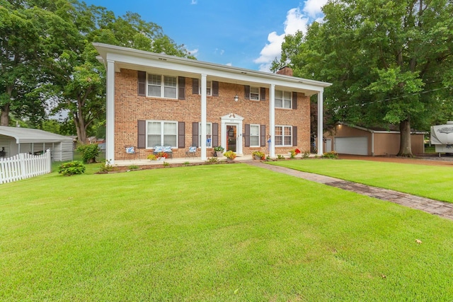 view of front of house with a garage, a front lawn, and an outbuilding