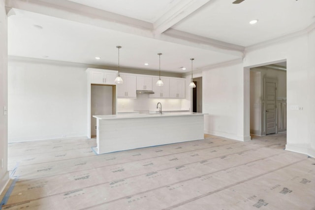 kitchen with hanging light fixtures, an island with sink, beamed ceiling, sink, and white cabinetry