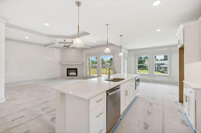 kitchen with sink, stainless steel appliances, white cabinets, decorative light fixtures, and a kitchen island with sink