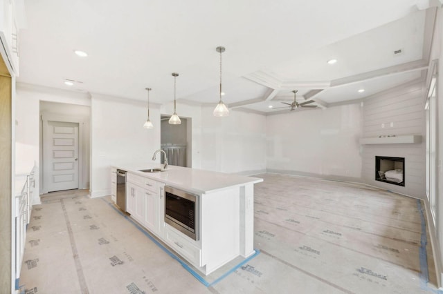 kitchen featuring decorative light fixtures, a center island with sink, a fireplace, appliances with stainless steel finishes, and sink