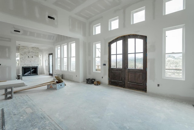 entryway with french doors, a high ceiling, and a stone fireplace