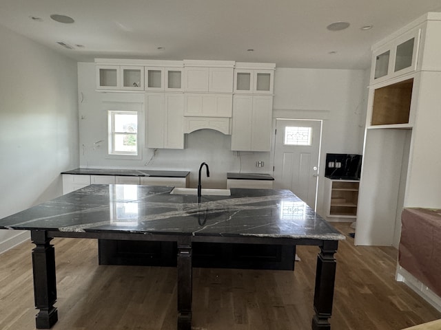 kitchen with hardwood / wood-style flooring, sink, dark stone countertops, and white cabinets