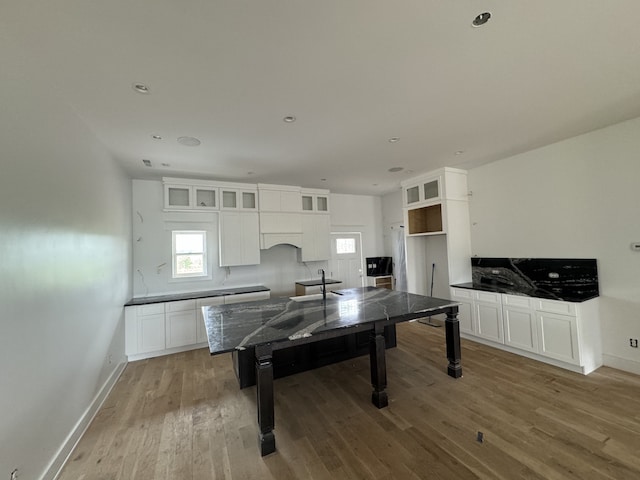 kitchen featuring white cabinetry, dark stone counters, and light hardwood / wood-style flooring