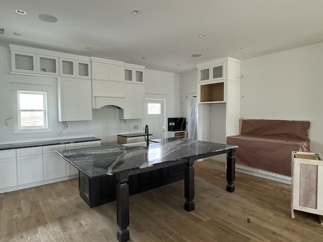 kitchen with dark stone counters, white cabinetry, and wood-type flooring