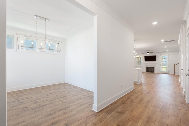 corridor with ornamental molding, a chandelier, and light hardwood / wood-style floors