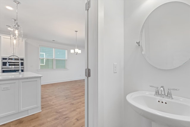 bathroom with wood-type flooring, sink, and a chandelier