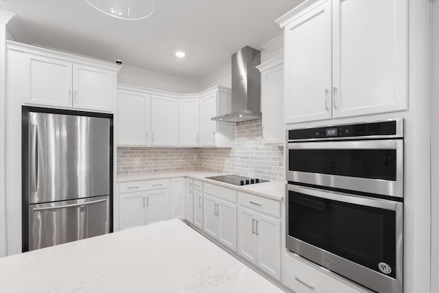 kitchen with white cabinetry, stainless steel appliances, decorative backsplash, and wall chimney range hood