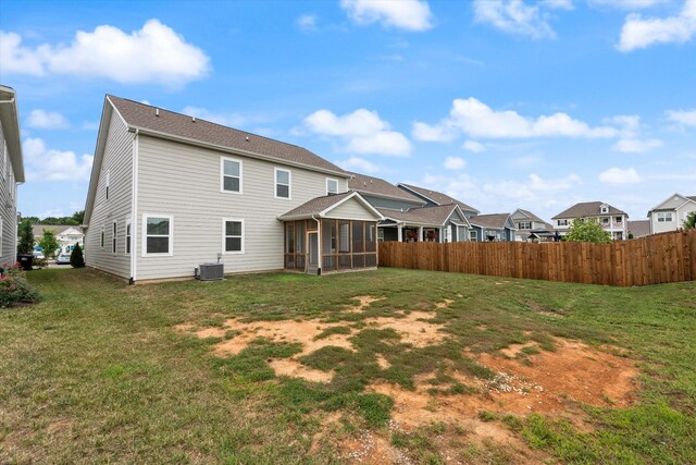 rear view of property featuring a yard, central AC, and a sunroom