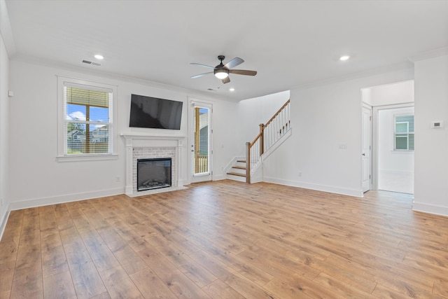 unfurnished living room with a brick fireplace, light hardwood / wood-style flooring, ornamental molding, and ceiling fan