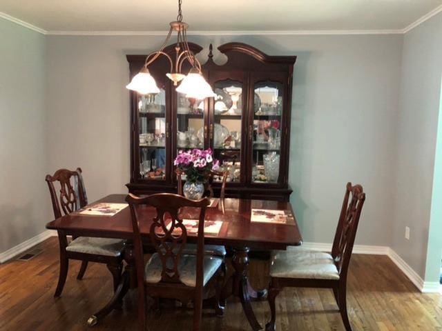 dining room with wood-type flooring, ornamental molding, and an inviting chandelier