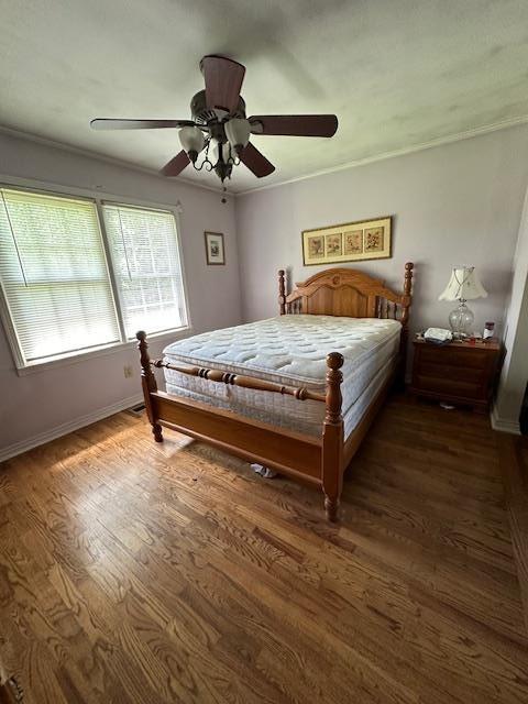 bedroom with crown molding, dark wood-type flooring, and ceiling fan