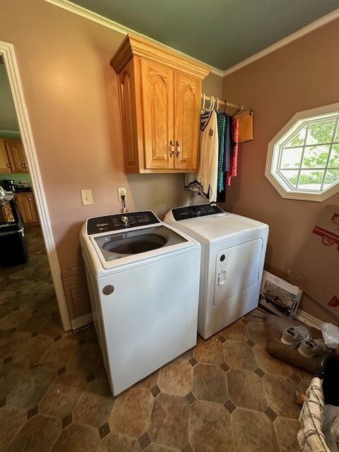 laundry room featuring washer and clothes dryer, crown molding, and cabinets