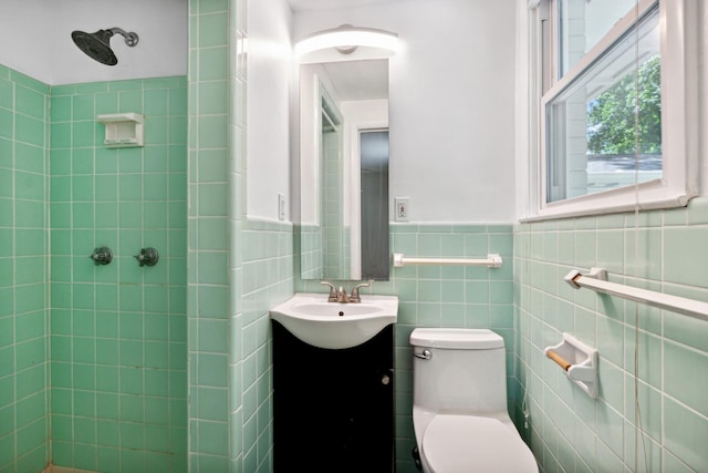 bathroom featuring vanity, toilet, tile walls, and tiled shower