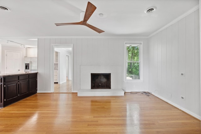 unfurnished living room featuring crown molding, light hardwood / wood-style floors, ceiling fan, and a brick fireplace