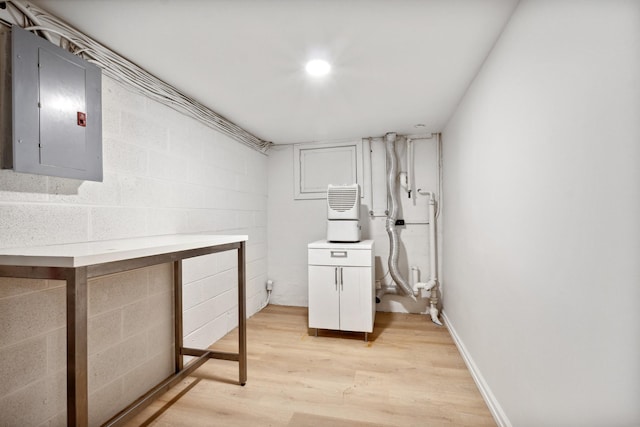 basement with light wood-type flooring and electric panel