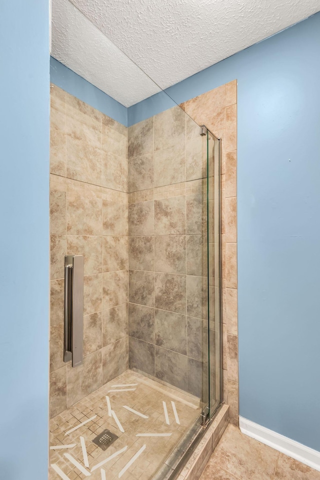 bathroom with an enclosed shower, tile patterned flooring, and a textured ceiling