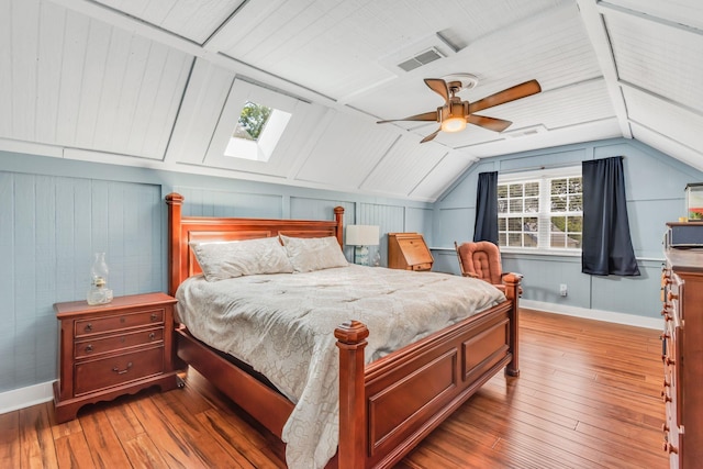 bedroom with ceiling fan, dark wood-type flooring, and vaulted ceiling with skylight