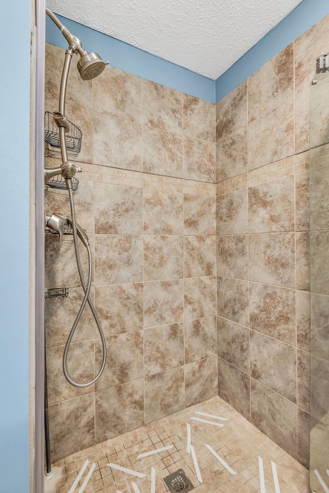 bathroom featuring a tile shower and a textured ceiling