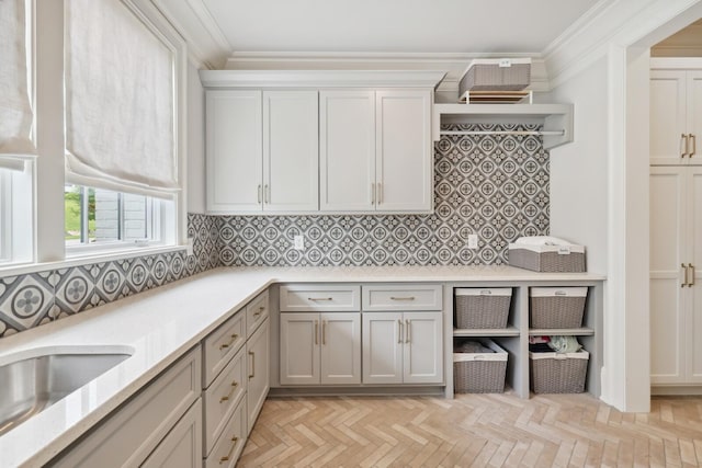 kitchen featuring ornamental molding, sink, light parquet flooring, and backsplash