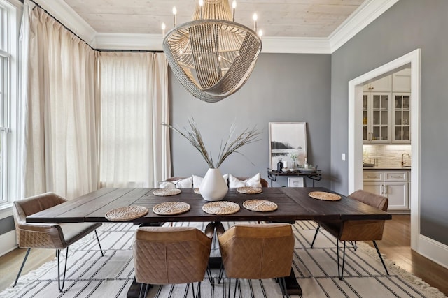 dining room with an inviting chandelier, sink, crown molding, and light hardwood / wood-style floors