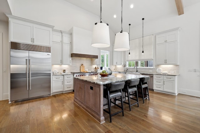 kitchen with white cabinetry, a center island, and stainless steel built in refrigerator