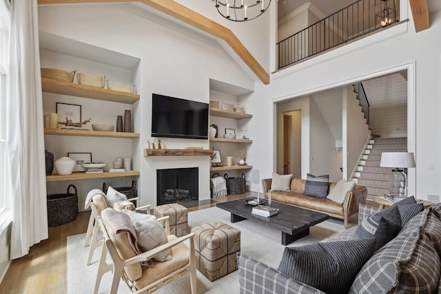 living room with built in shelves, high vaulted ceiling, light hardwood / wood-style flooring, and a notable chandelier