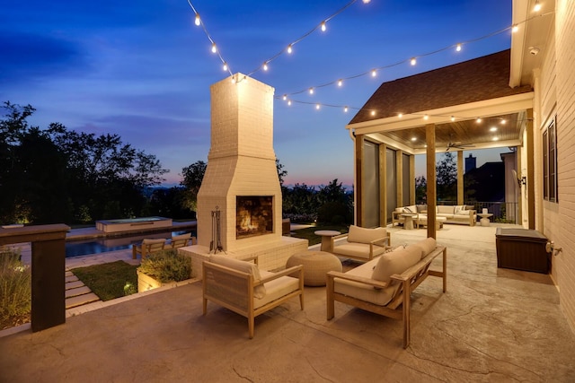 patio terrace at dusk with an outdoor living space with a fireplace and a pool with hot tub