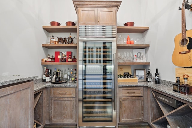 bar with beverage cooler, black dishwasher, and stone counters