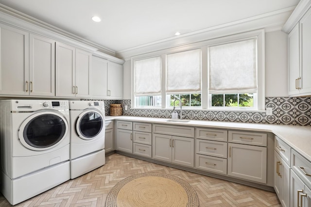 laundry area featuring sink, crown molding, cabinets, independent washer and dryer, and light parquet flooring